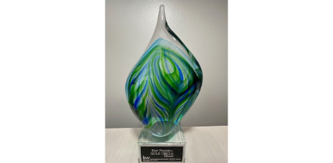 Covered porch with seating; white walls, gray floor, wood ceiling, black-framed doors/windows, potted flowers.