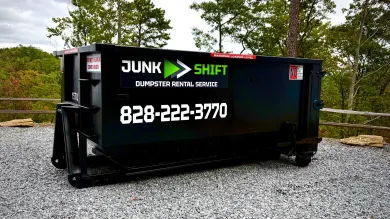 A dumpster is parked in a driveway next to a house.