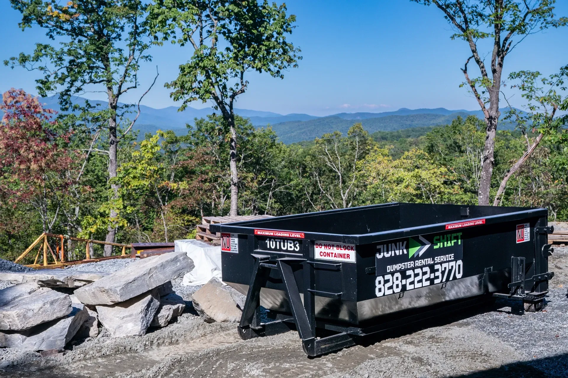 A dumpster is being pulled by a truck on a trailer.