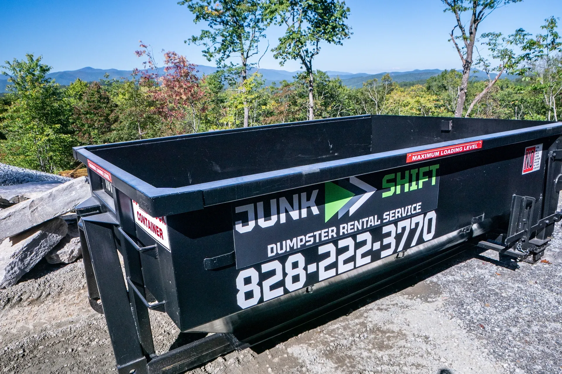 A dumpster is being pulled by a truck on a trailer.
