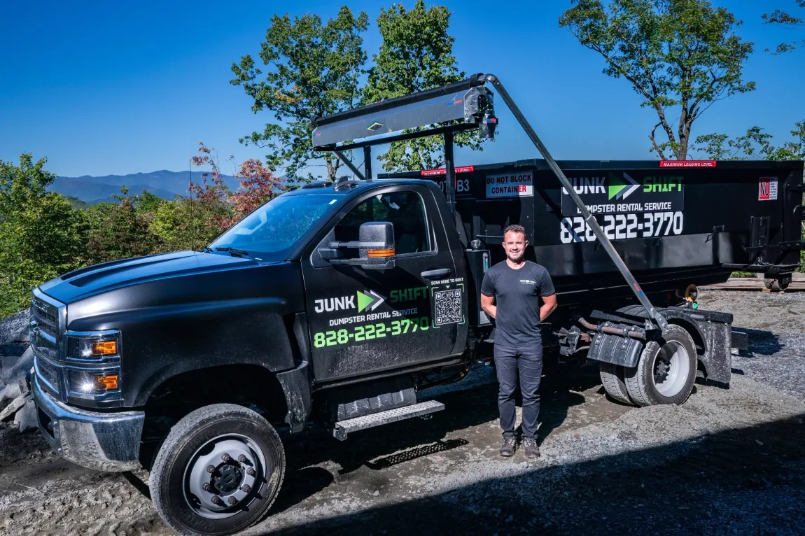 A group of people standing in front of a dumpster.