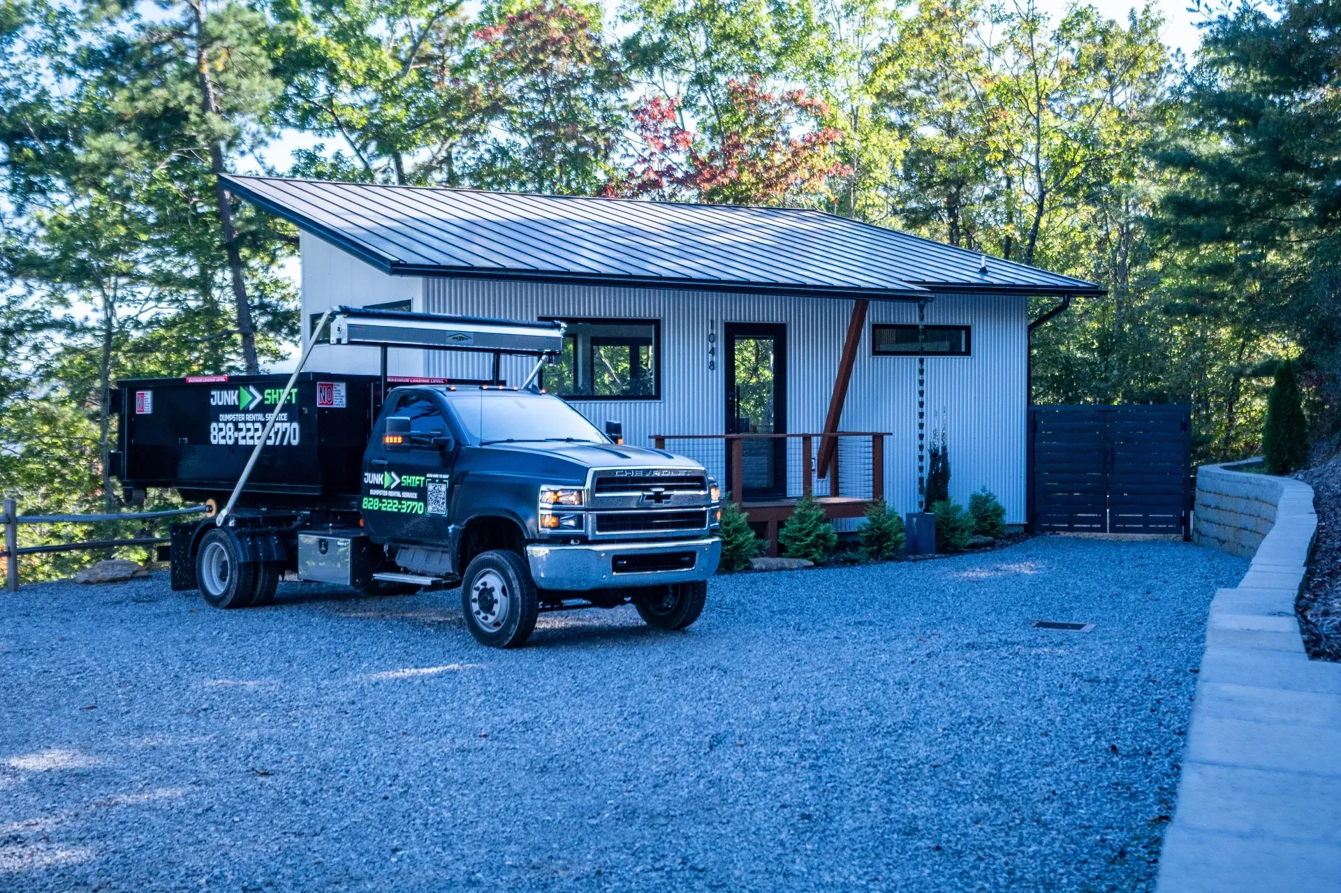 A dumpster is parked in the snow in front of a house.