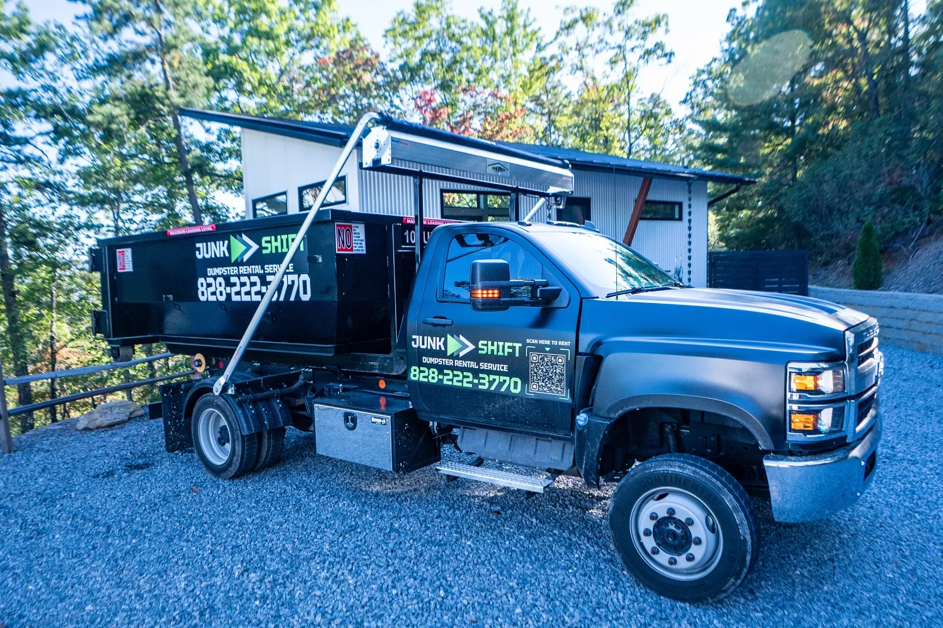 A dumpster is parked in the snow in front of a house.