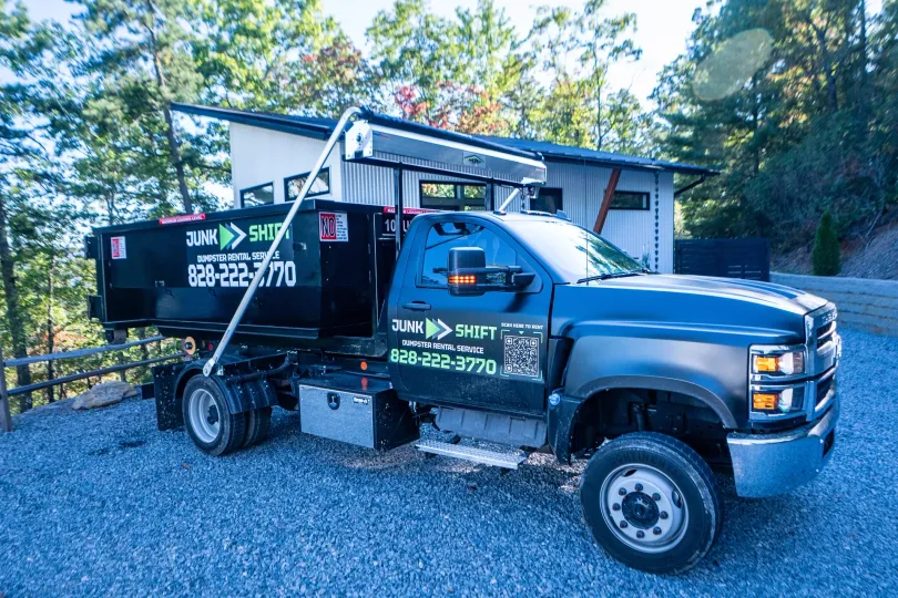 A woman is standing in front of a dumpster.