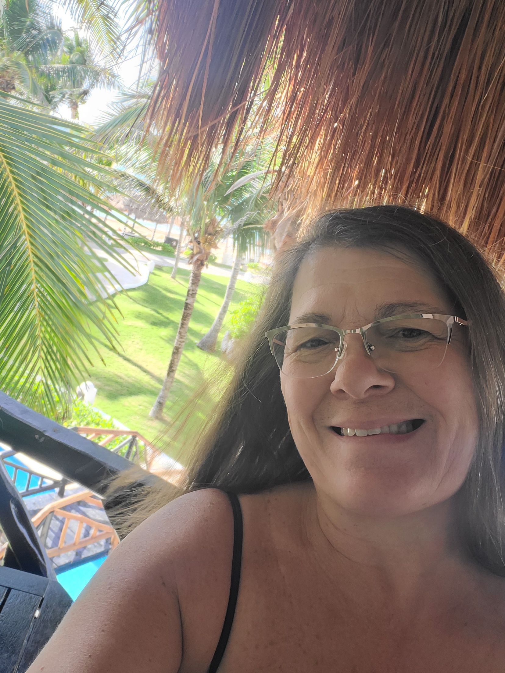 Family of five with backpacks on mountain, arms raised, against a sunny sky.