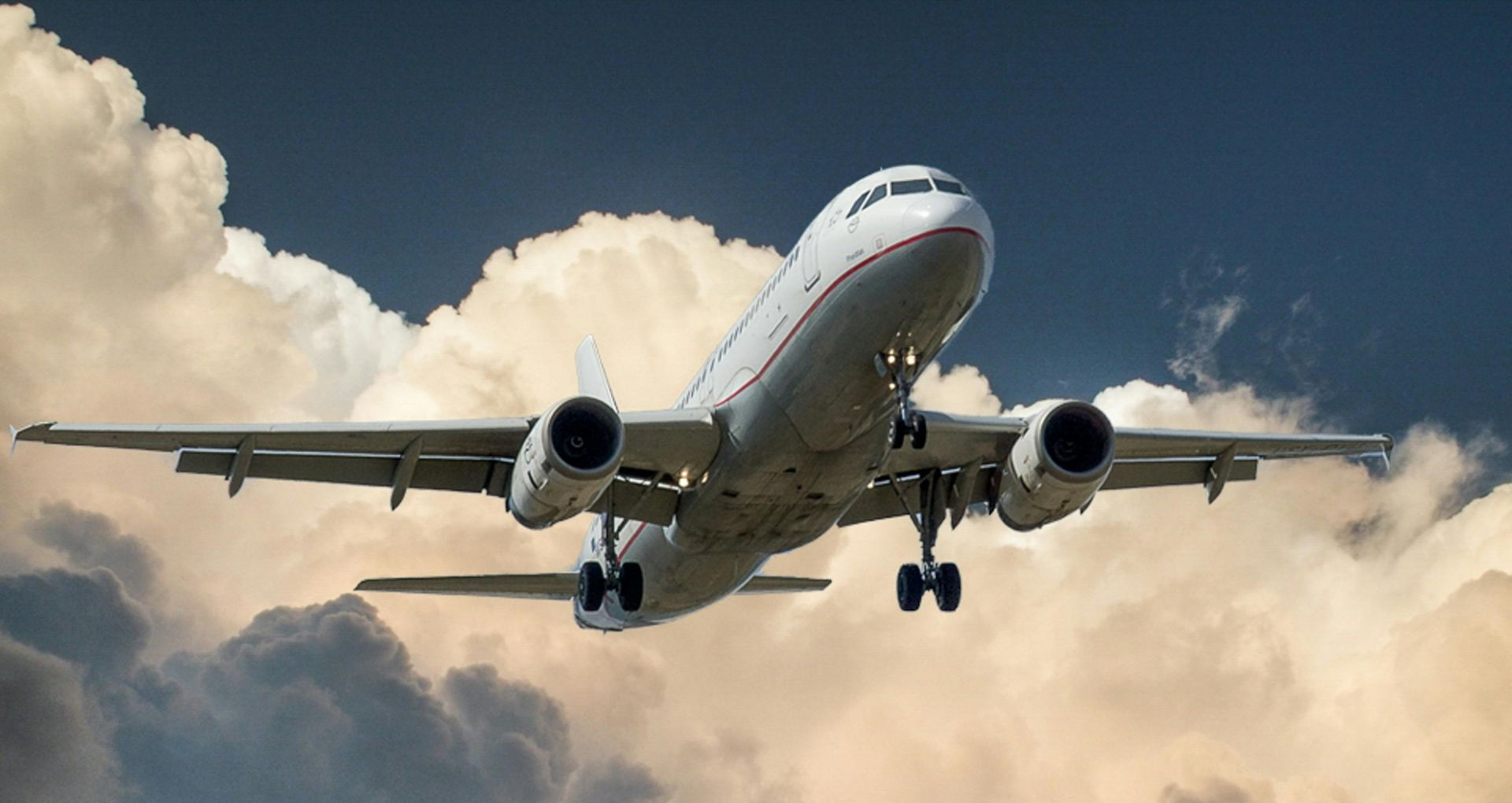 A passenger jet taking off against a cloudy, blue sky.