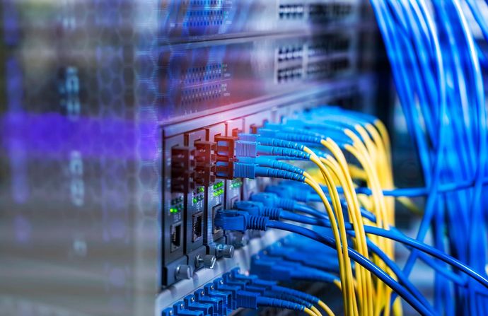 Un rack per server di rete con diversi cavi Ethernet blu e gialli collegati alle porte dello switch in un data center.