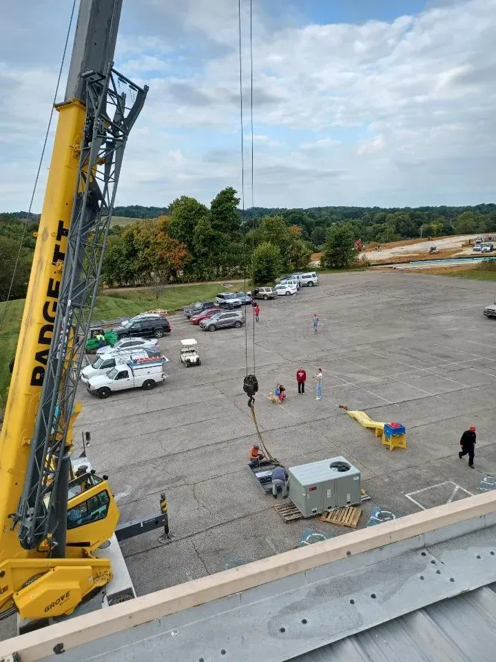A large yellow crane is lifting a box in a parking lot.