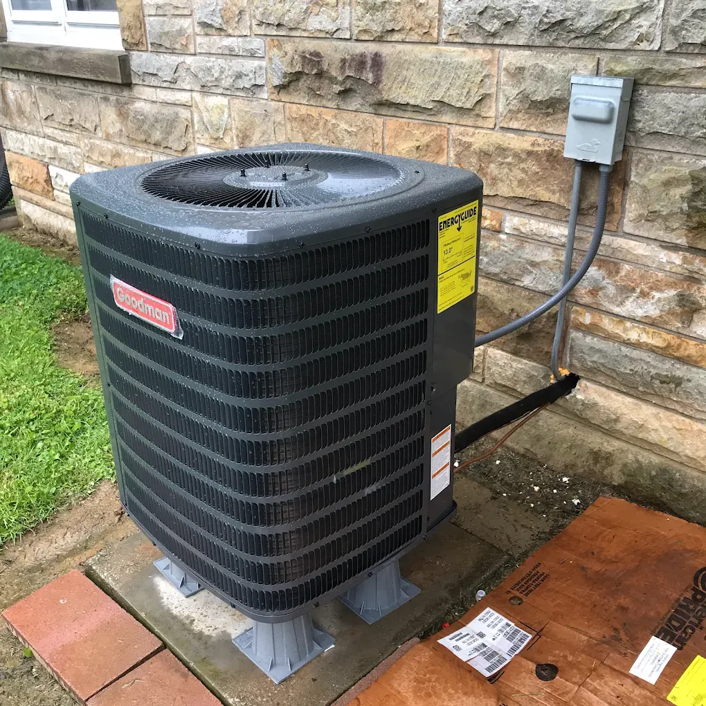 An air conditioner is sitting on the side of a brick building.