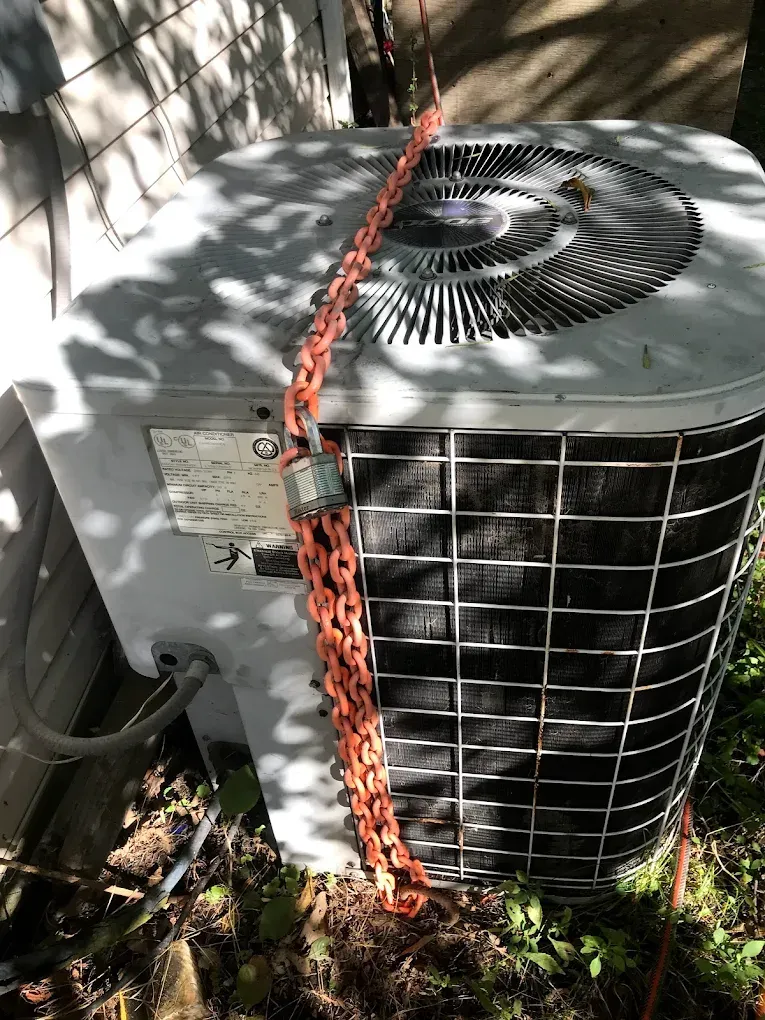 A close up of an air conditioner with a chain around it.