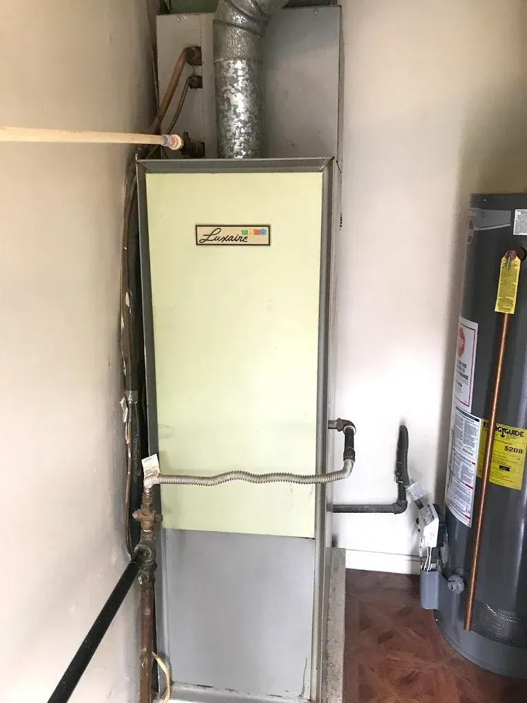 A gas heater is sitting next to a water heater in a room.