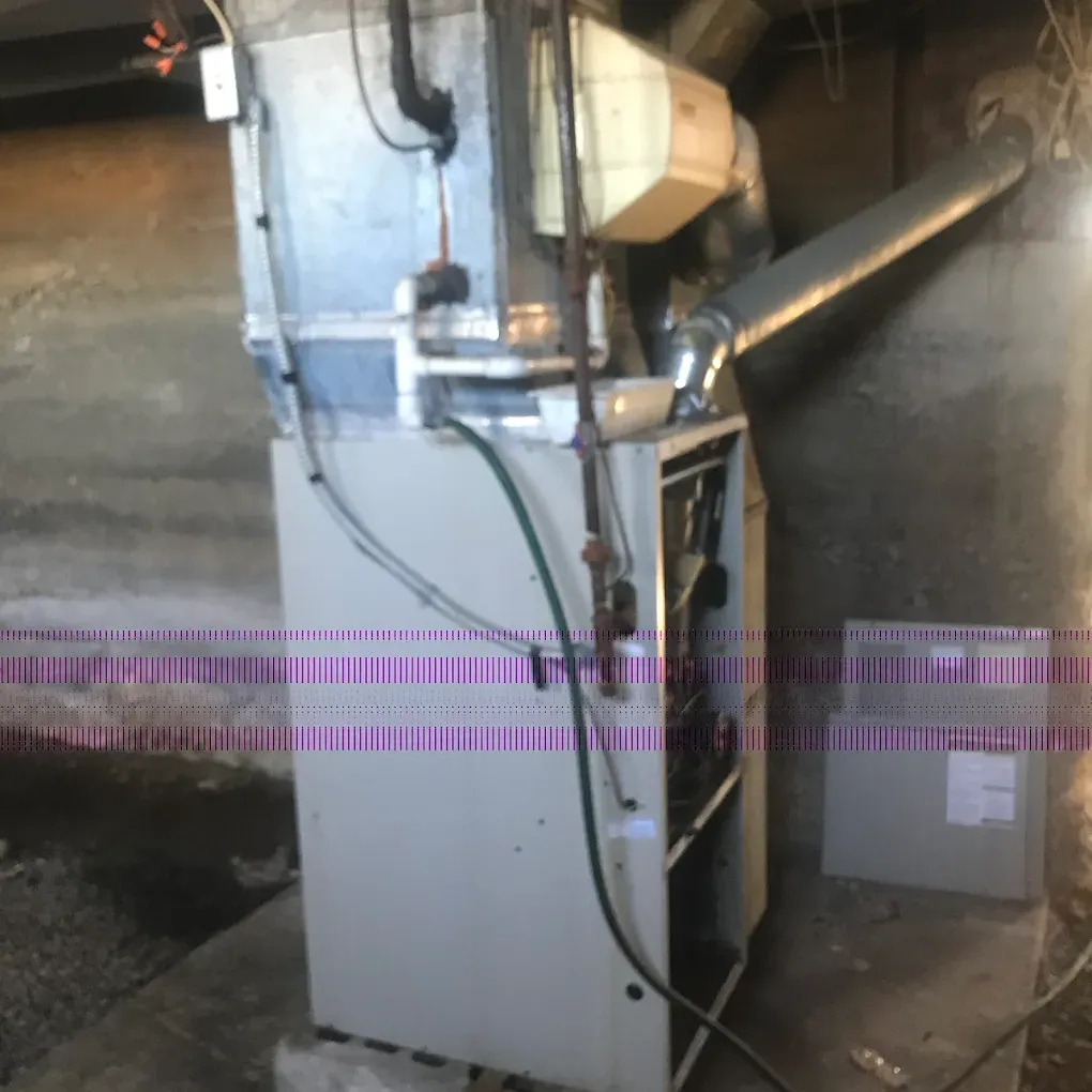 An air conditioner is sitting in a basement next to a wall