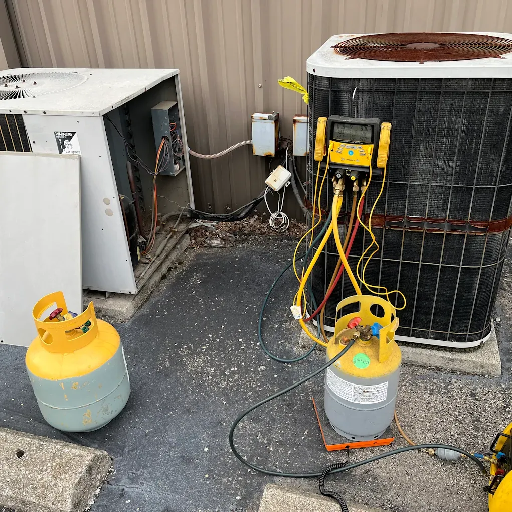 A propane tank is sitting next to an air conditioner.