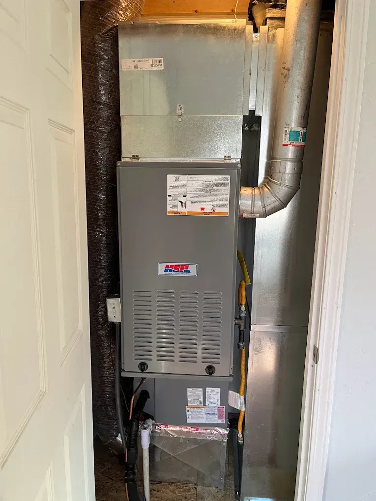 A furnace is sitting in a closet next to a door.