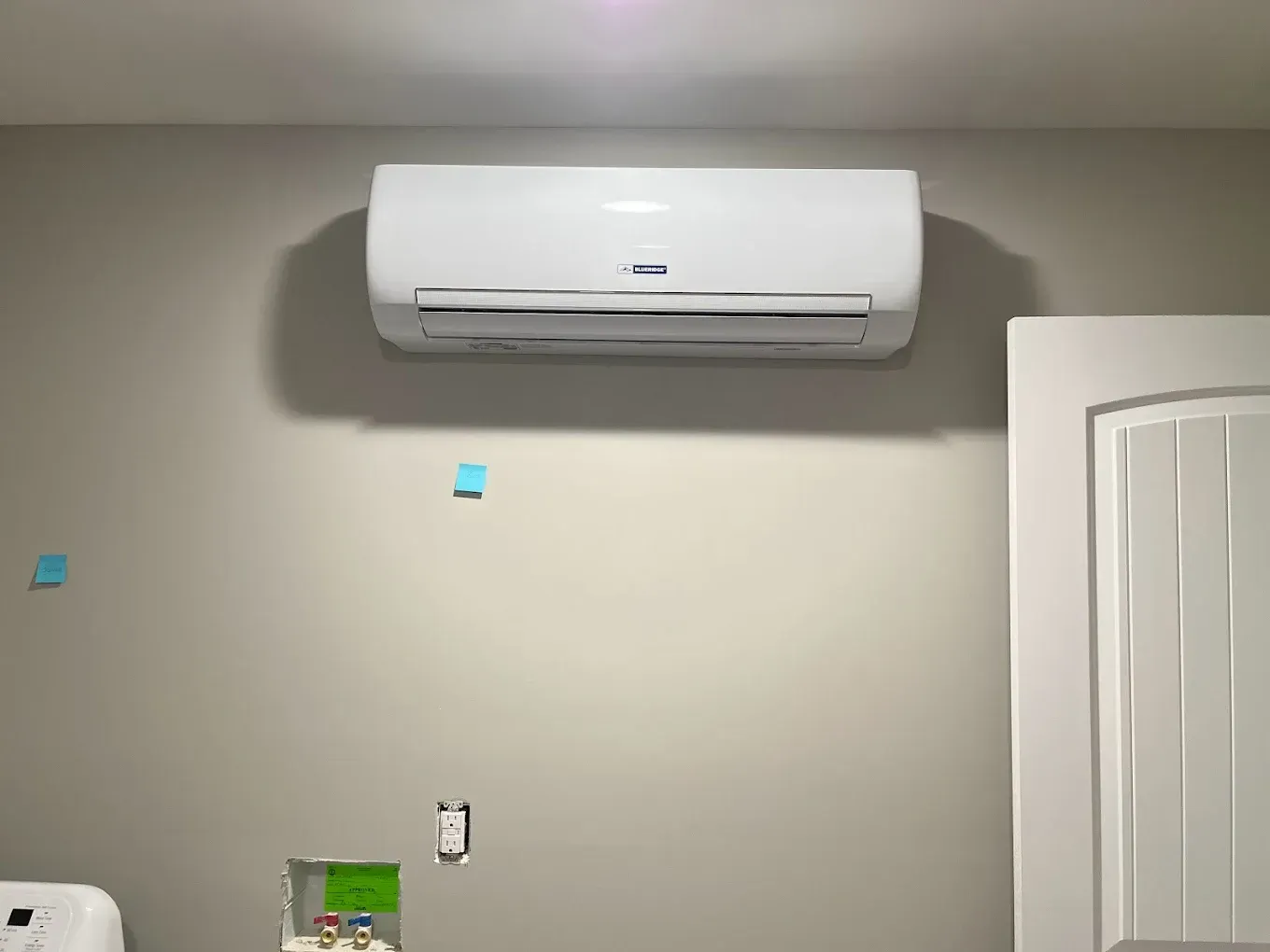 A white air conditioner is hanging on a wall in a room.
