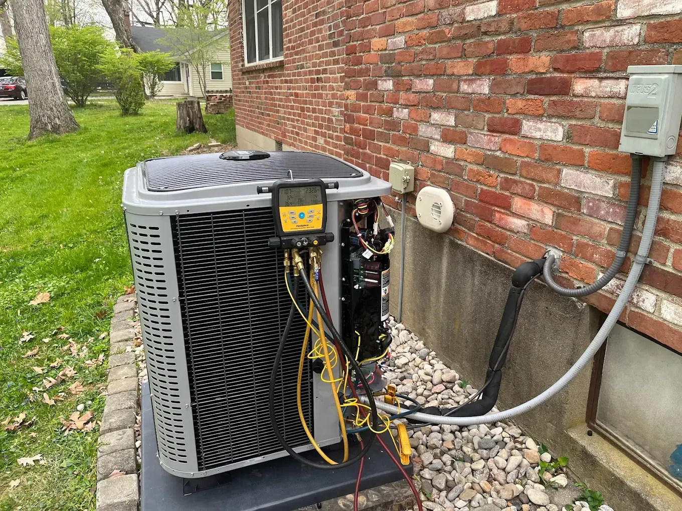 An air conditioner is being installed on the side of a brick building.