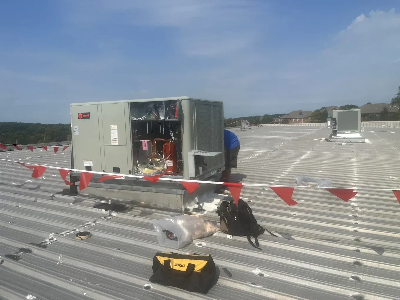 A man is working on an air conditioner on the roof of a building.