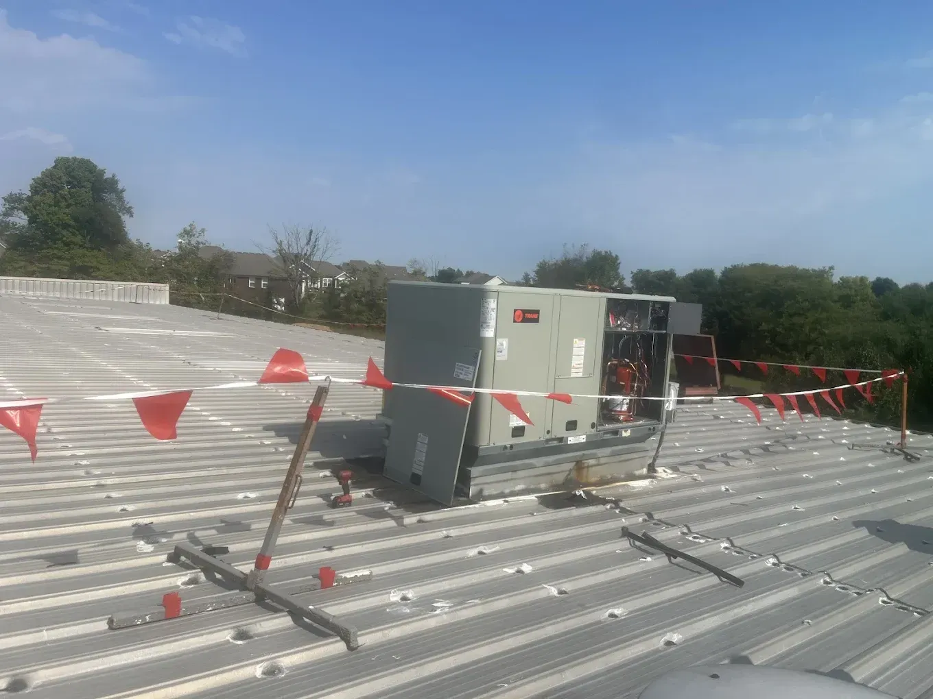 An air conditioner is sitting on top of a metal roof.