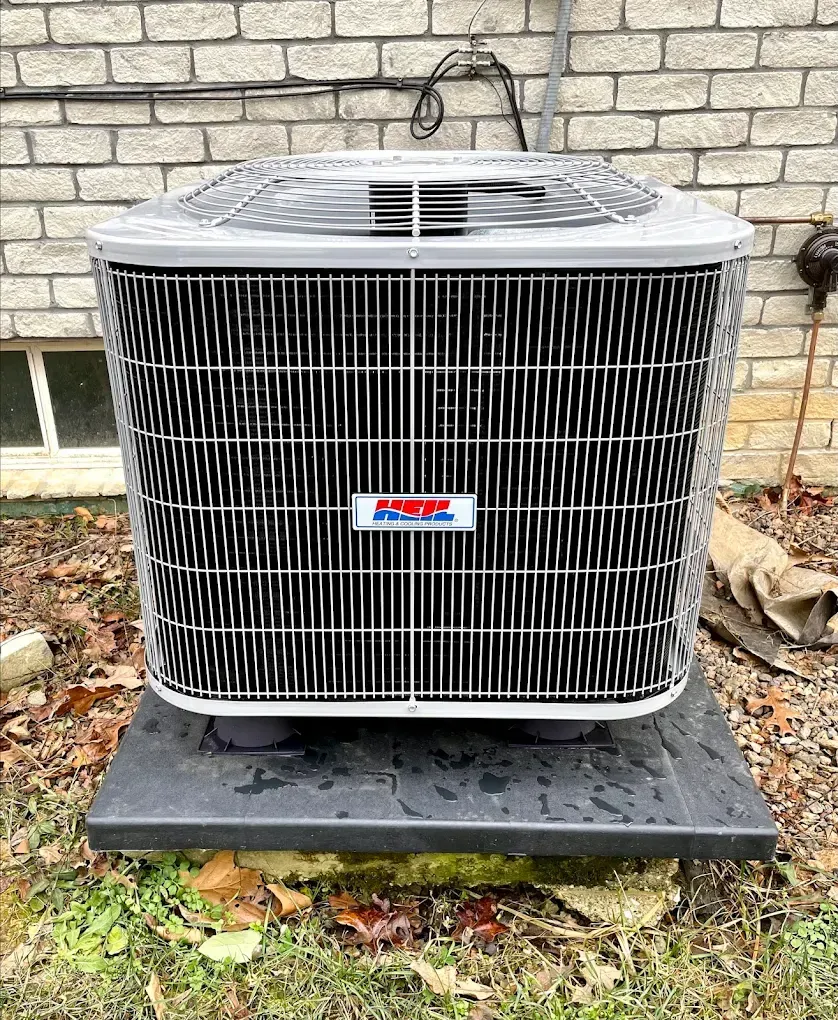 An air conditioner is sitting outside of a brick building.