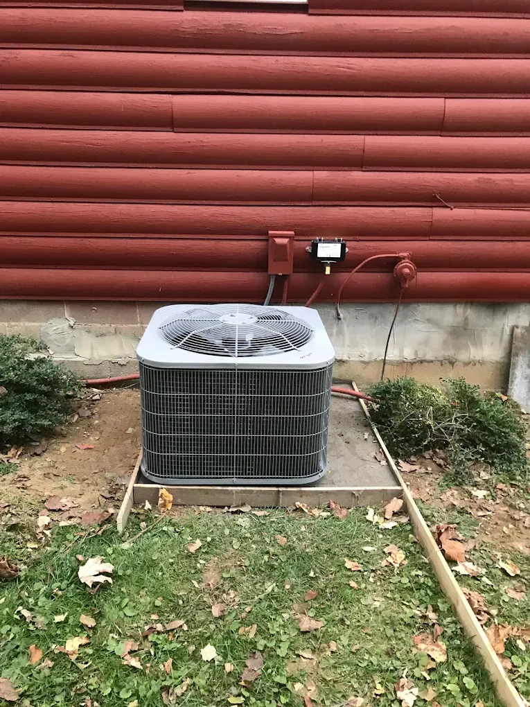 An air conditioner is sitting outside of a log cabin.
