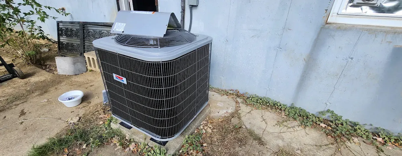 An air conditioner is sitting on the side of a building next to a window.