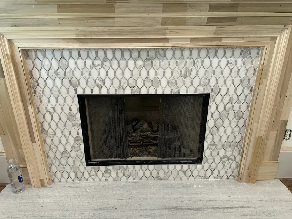 Fireplace with white oval tile surround and wooden mantel. Black firebox.