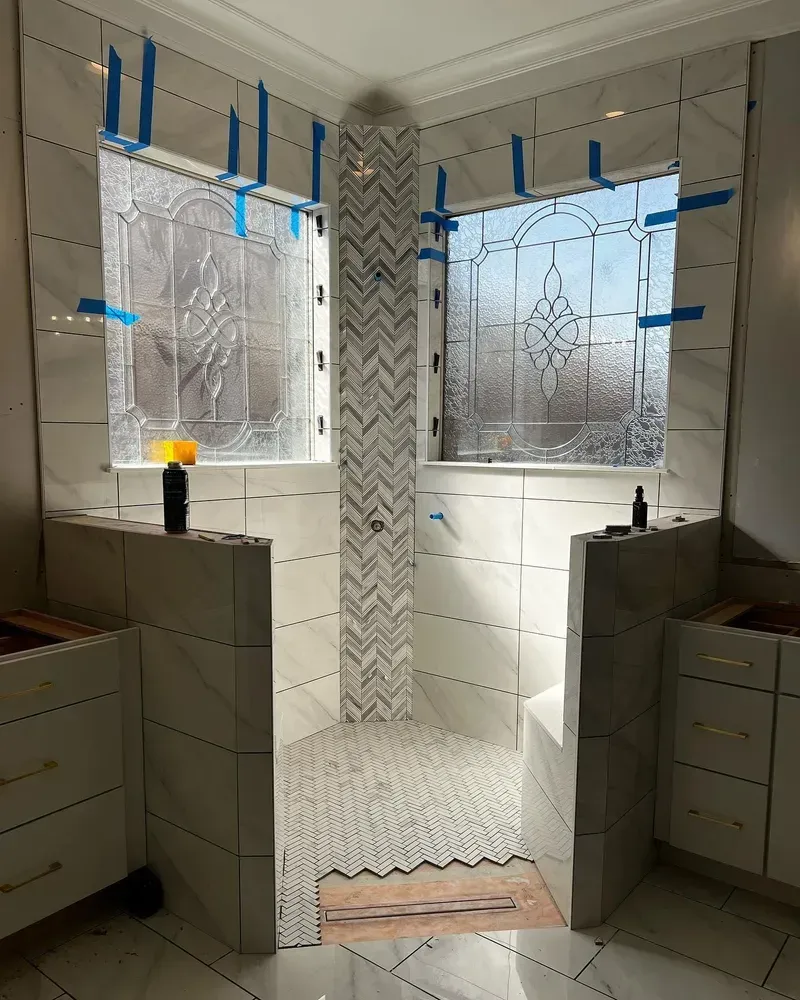 Newly tiled shower with glass block windows. White and gray tile, herringbone pattern in center.