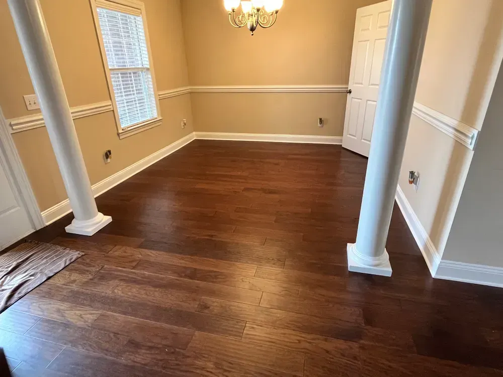 Dining room with hardwood floor, pillars, a window, and a chandelier.