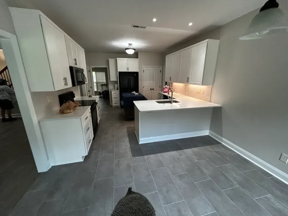 Modern kitchen with white cabinets, quartz countertops, and gray tile flooring.