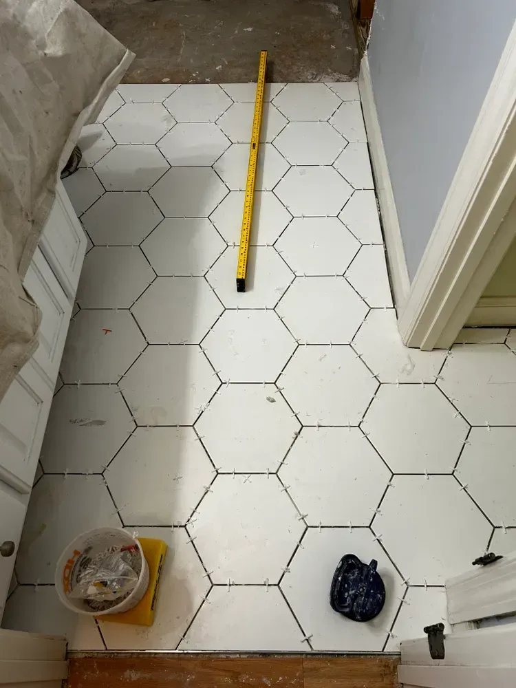 White hexagon tile bathroom floor with yellow tape measure.