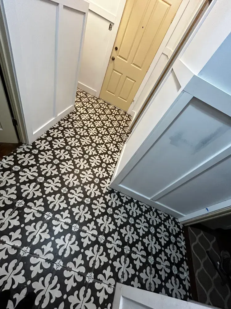 Entryway with patterned black and white tile flooring, white trim, and a yellow door.