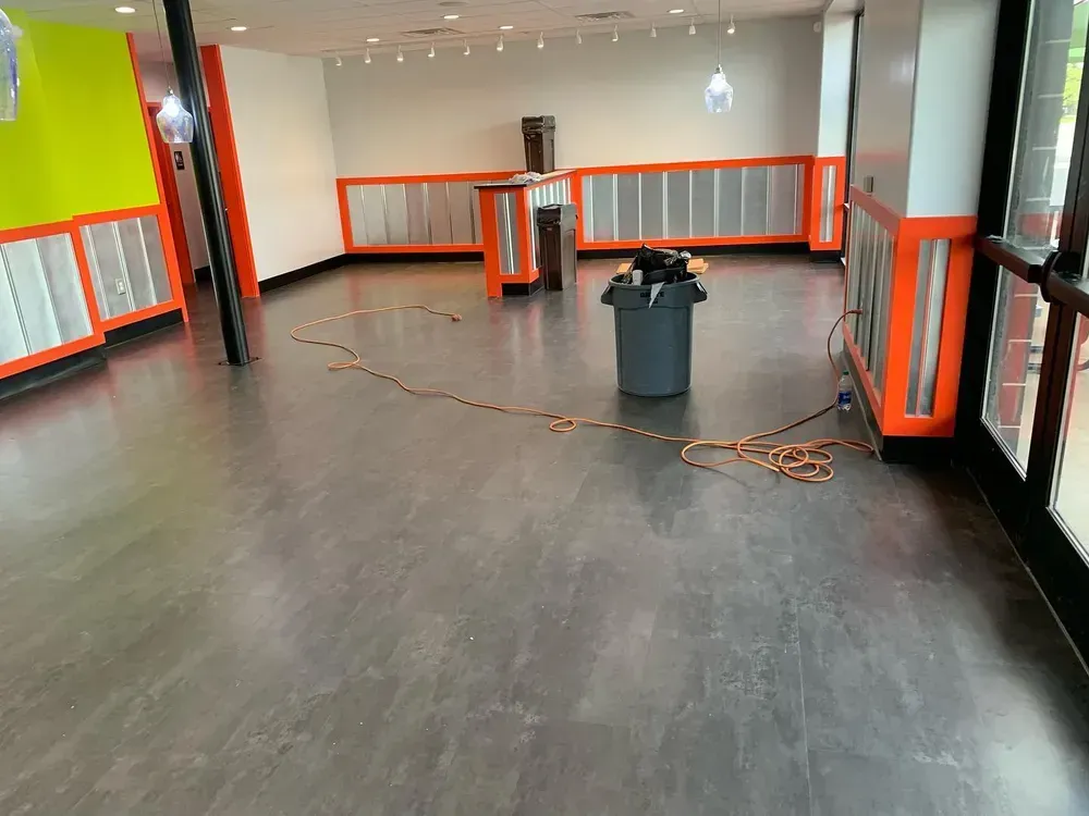 Empty commercial space with gray floors, orange and white walls, and bright green accents.