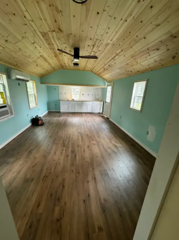 Interior view of room with wood floor and ceiling, blue walls, cabinets, and a ceiling fan.