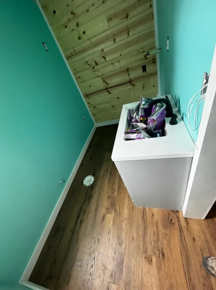 Interior room with turquoise walls, wood plank accent, and a gray counter holding supplies.