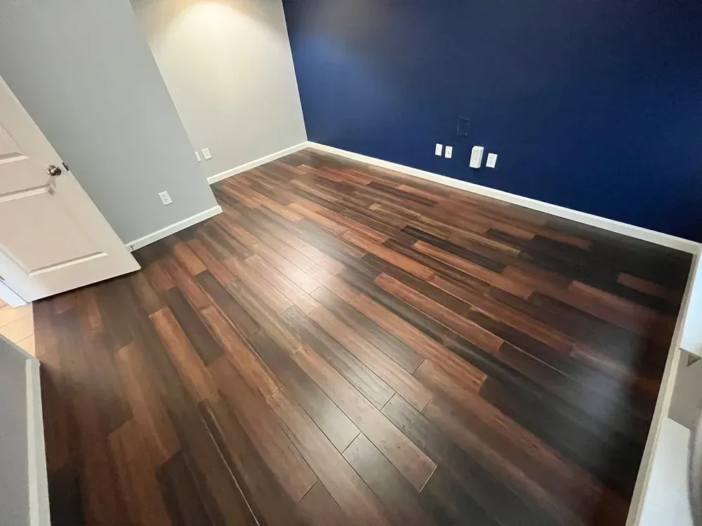 Dark wood floor in a room with blue and gray walls. White trim and door.