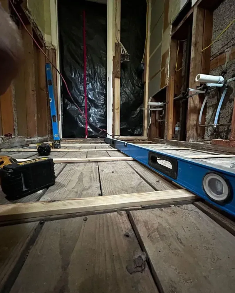 Bathroom renovation, wooden floor with level and construction materials.