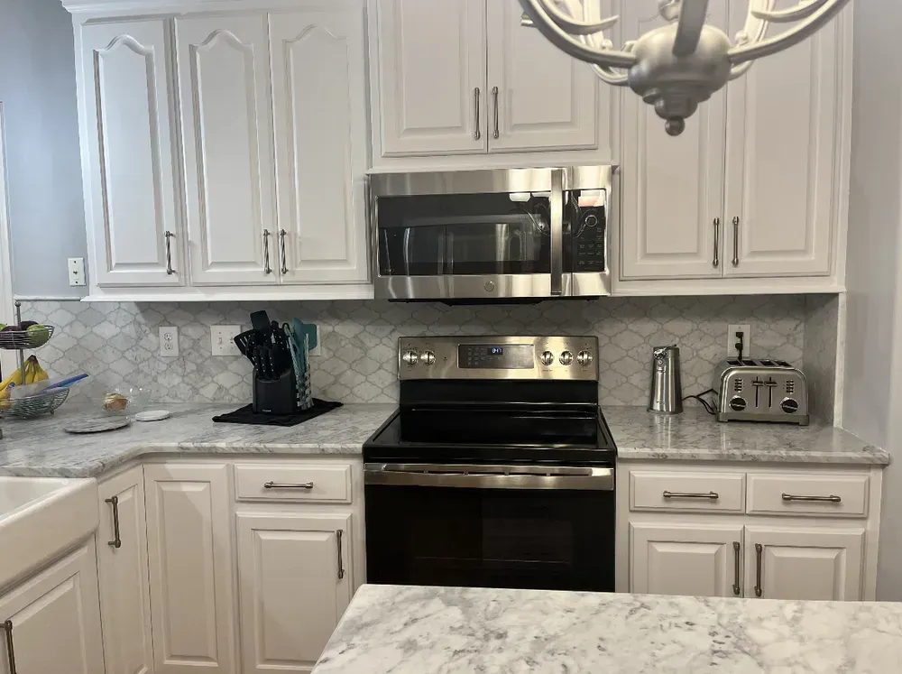 White kitchen with stainless steel appliances and granite countertops.