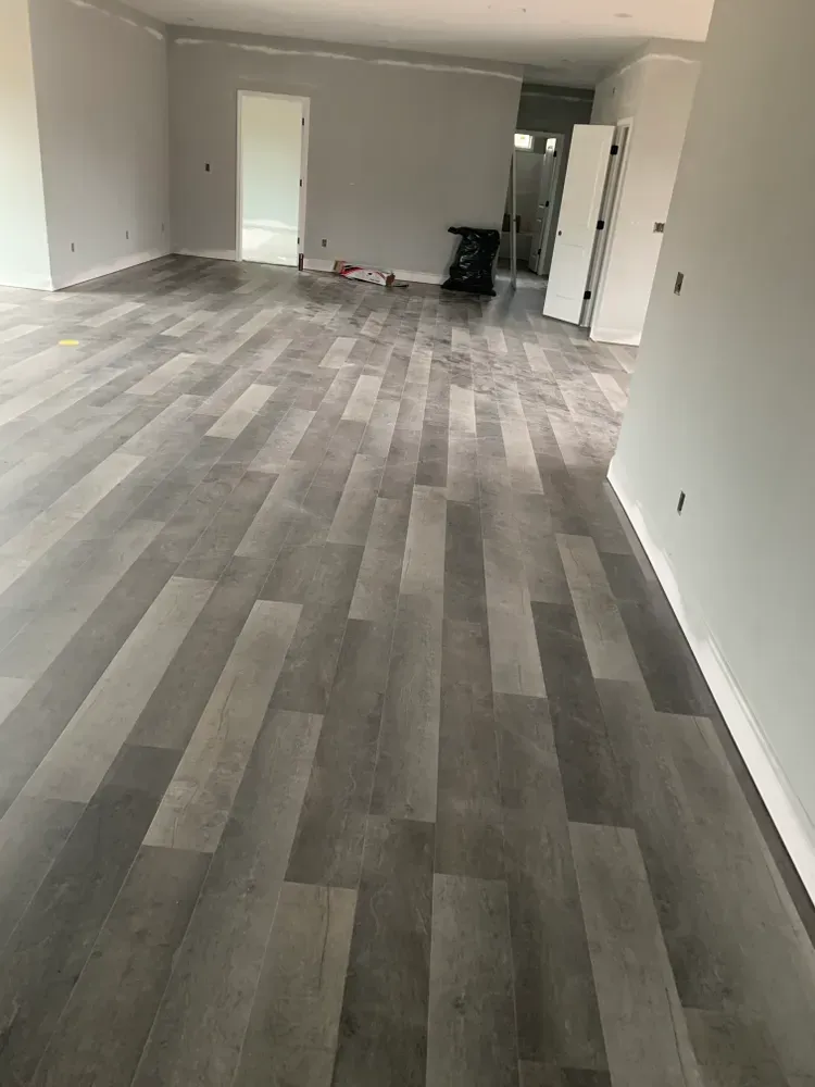 Gray wood-look flooring installed in a room with light gray walls and an open doorway.