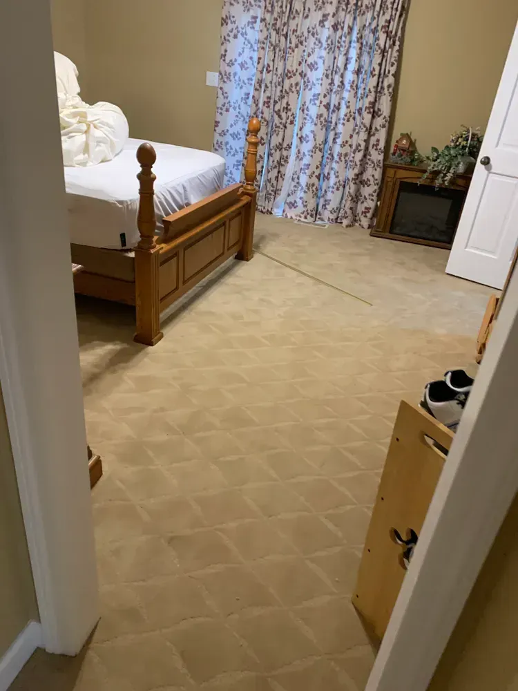 Bedroom with a bed, patterned carpet, floral curtains, and a fireplace.