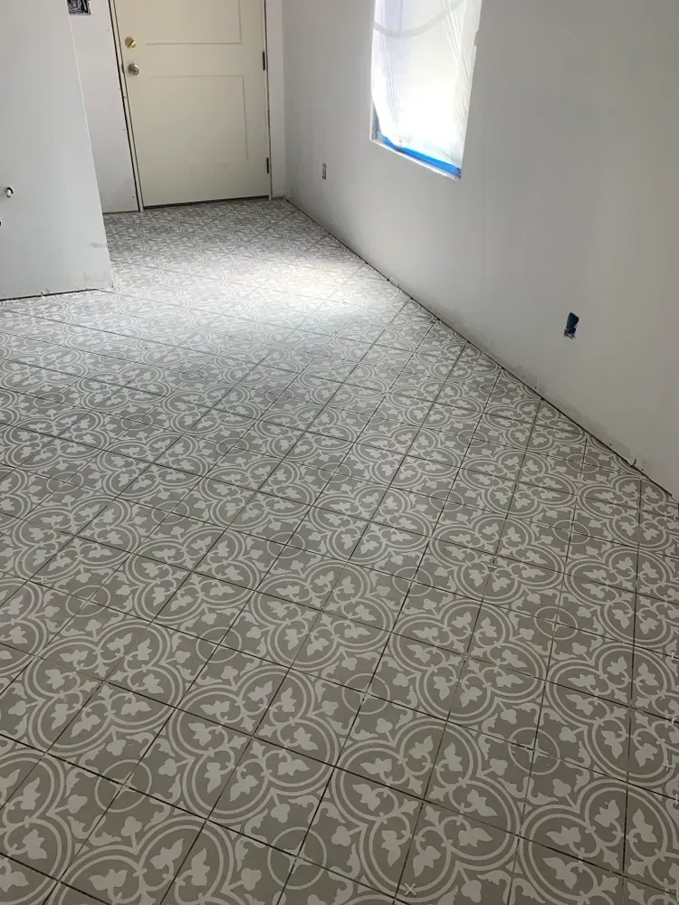 Grey and white patterned tile flooring in a room with white walls and a door.