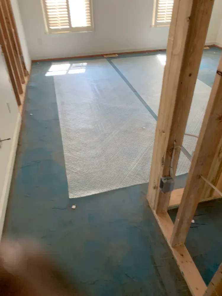 Blue concrete floor with bubble wrap, partially covered by wooden framing in a room.