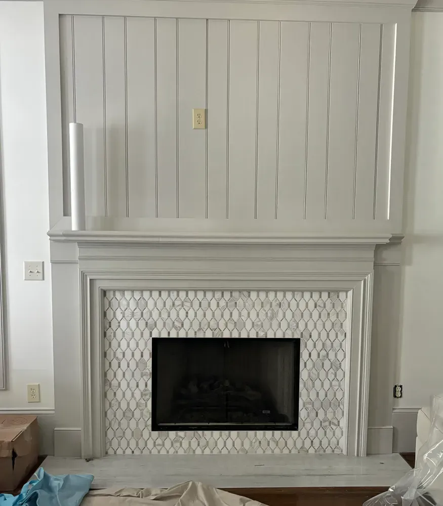Gray fireplace with white mosaic tile and wavy vertical paneling.