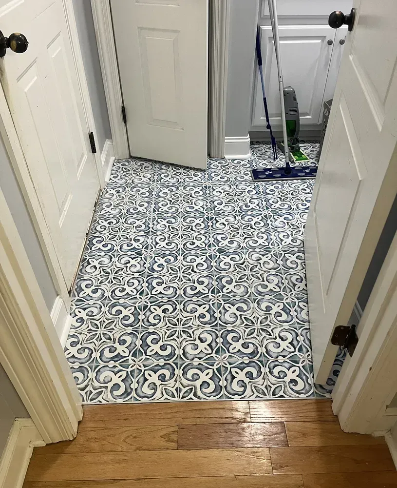Hallway with blue and white patterned tile floor and two white doors.