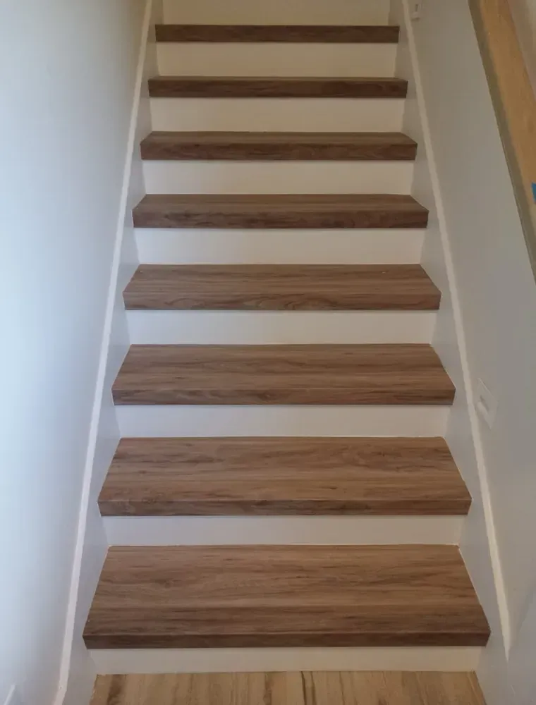 Staircase with brown wooden steps, white risers, and white walls.