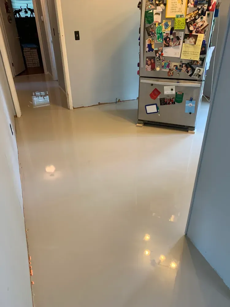 Hallway with shiny, light-colored floor; refrigerator with magnets on right.