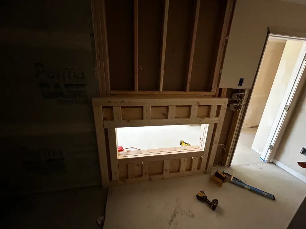 Fireplace framing under construction; wooden structure with open cavity, drywall, and tools nearby.