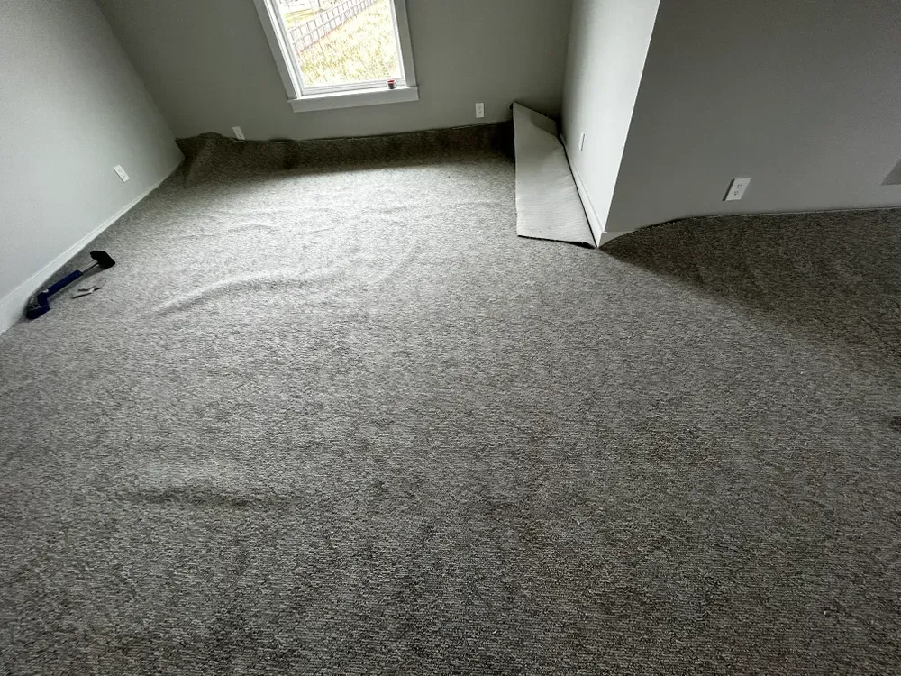 Beige carpet being installed in a room with a small window.