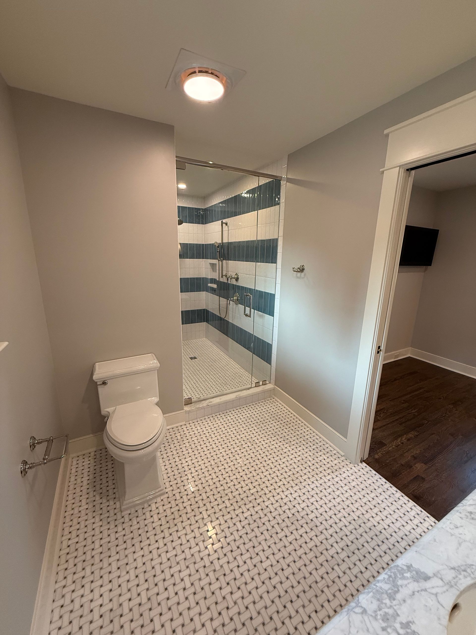 Bathroom with white and blue striped shower, white toilet, and tile floor; doorway on right.