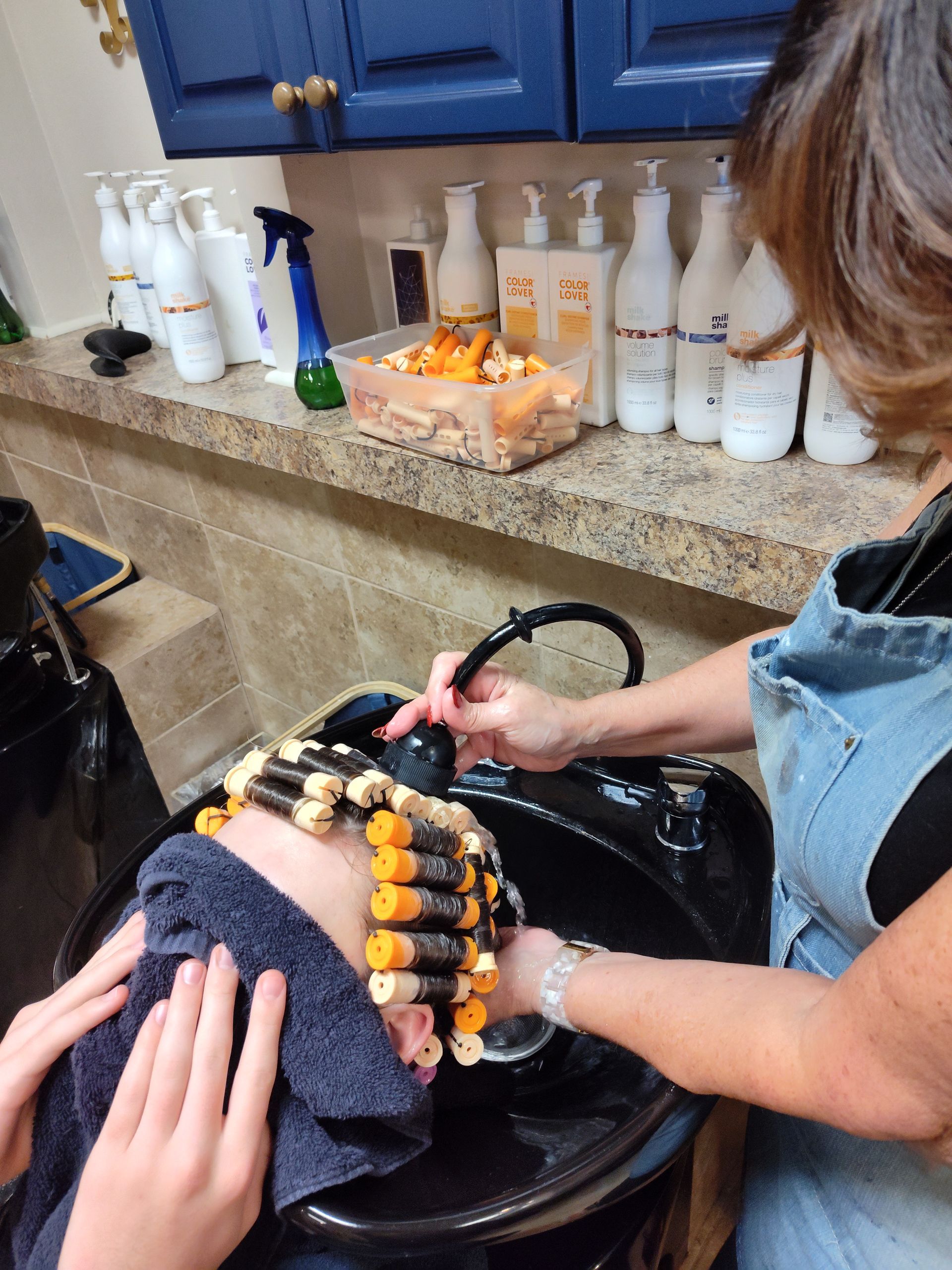 A woman is washing a person 's hair in a sink