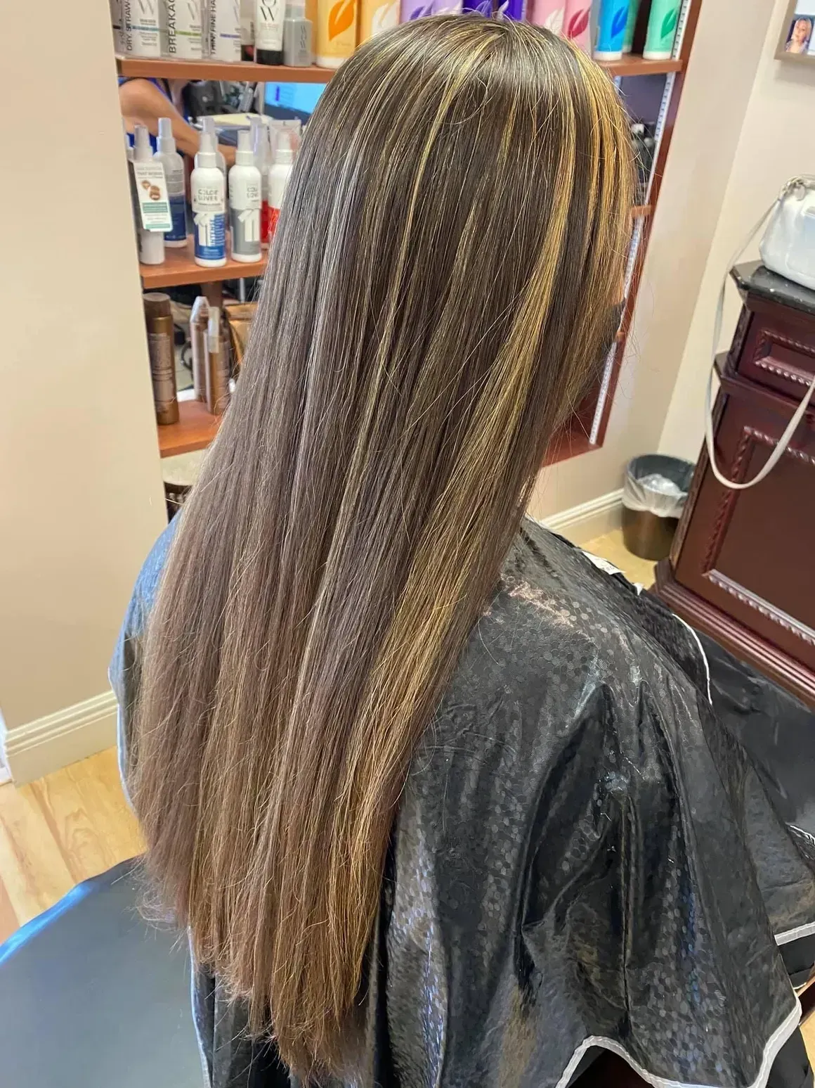 A woman with long hair is sitting in a chair in a salon.